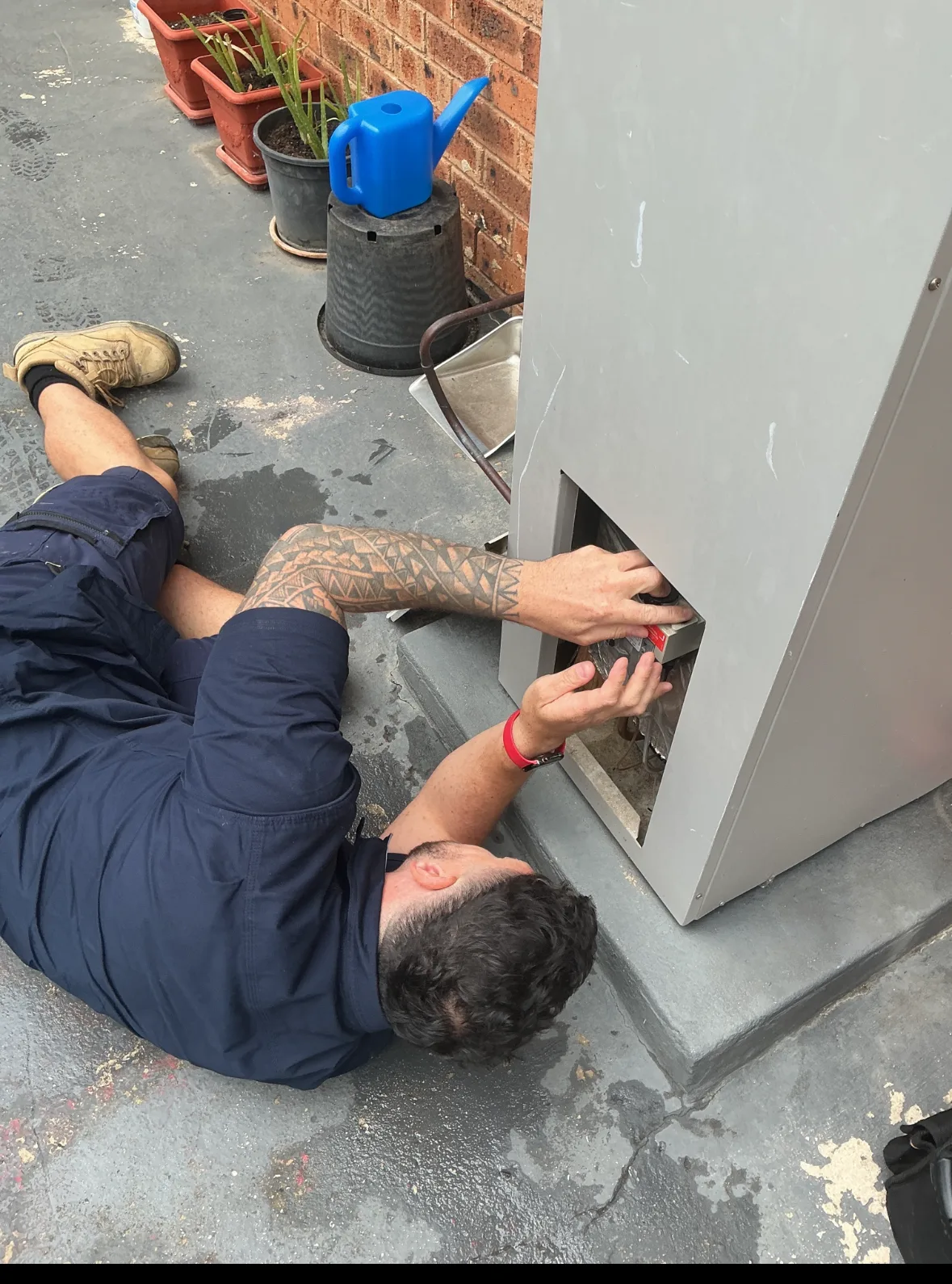 Tommy from TotalCare inspecting an outdoor hot water unit