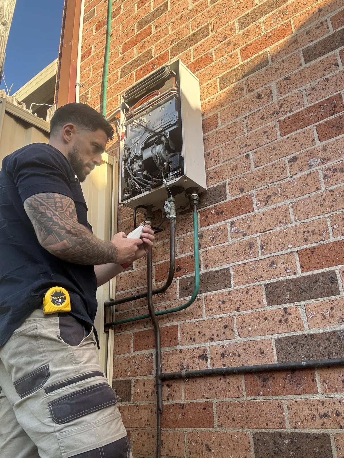 Tommy from TotalCare working beside an outdoor hot water system
